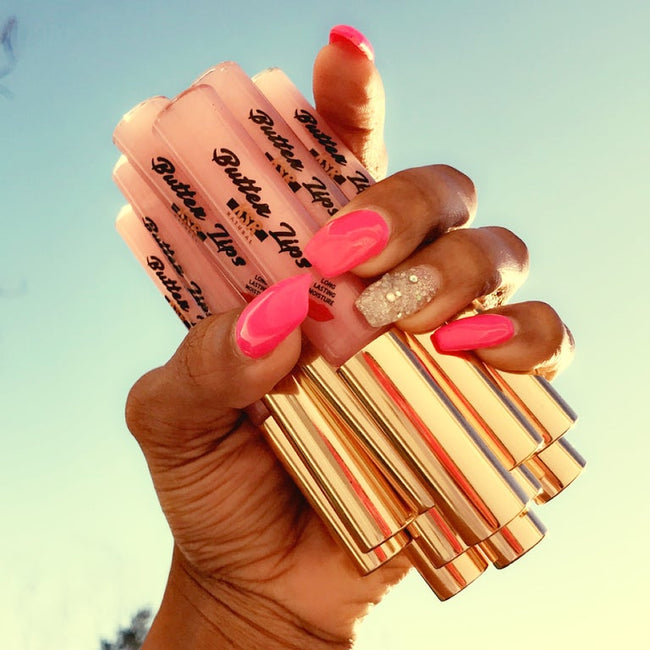 five tubes of the KSR Natural Butter Lips in 'Doll Baby'. Held by manicured pink and white nails.