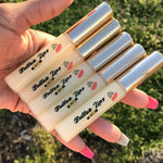 five tubes of the original KSR Natural Butter Lips, in 'Butter'. Held by manicured pink and white nails.